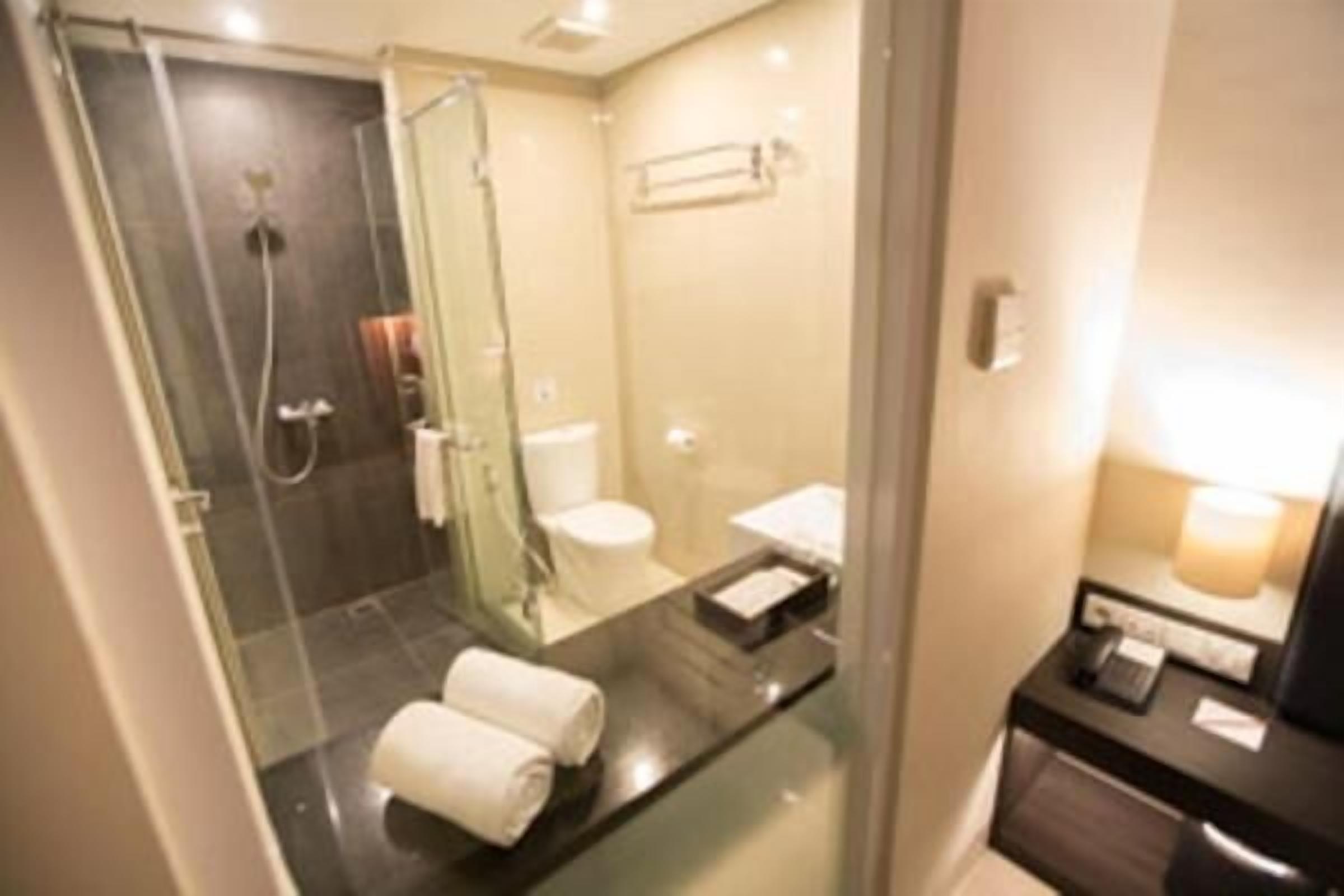 A modern bathroom with a glass shower enclosure, a separate toilet, and a vanity with a mirror.