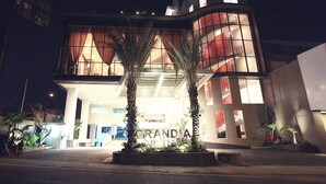 A modern hotel with a prominent entrance, large windows, and a well-lit facade. - Grandia Hotel (Bandung)