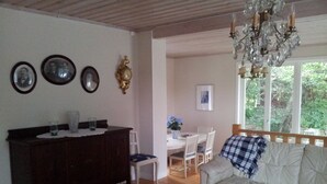 A cozy living room with a wooden floor, a sofa, a coffee table, a dining table with chairs, and a chandelier. - Brunnsta Gård (Balsta)