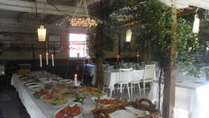 A long dining table set with various dishes, candles, and a wicker basket. - Brunnsta Gård (Balsta)