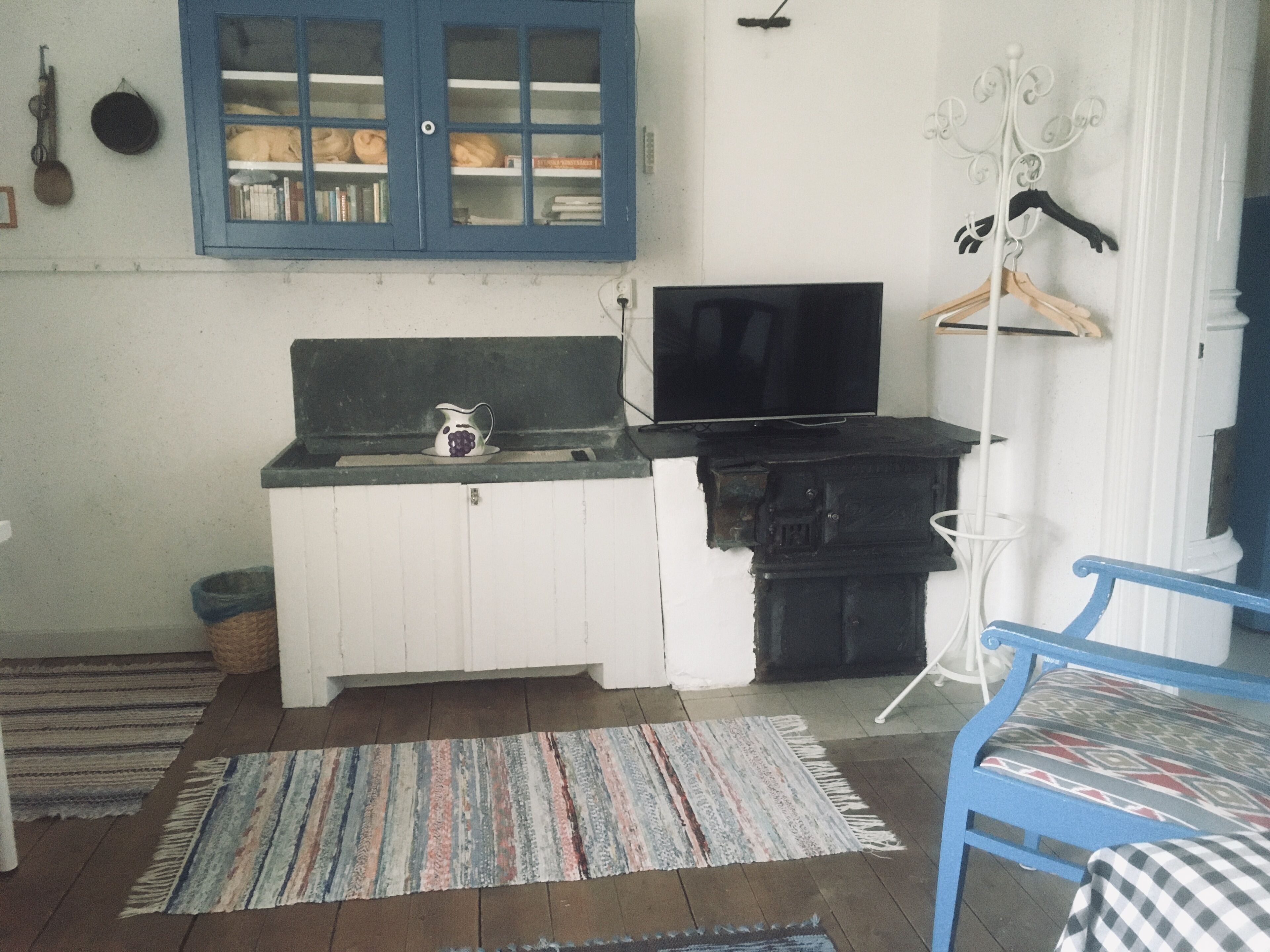 Eine kleine Küche mit Spüle, Fernseher und einer Schrank mit Glastüren.