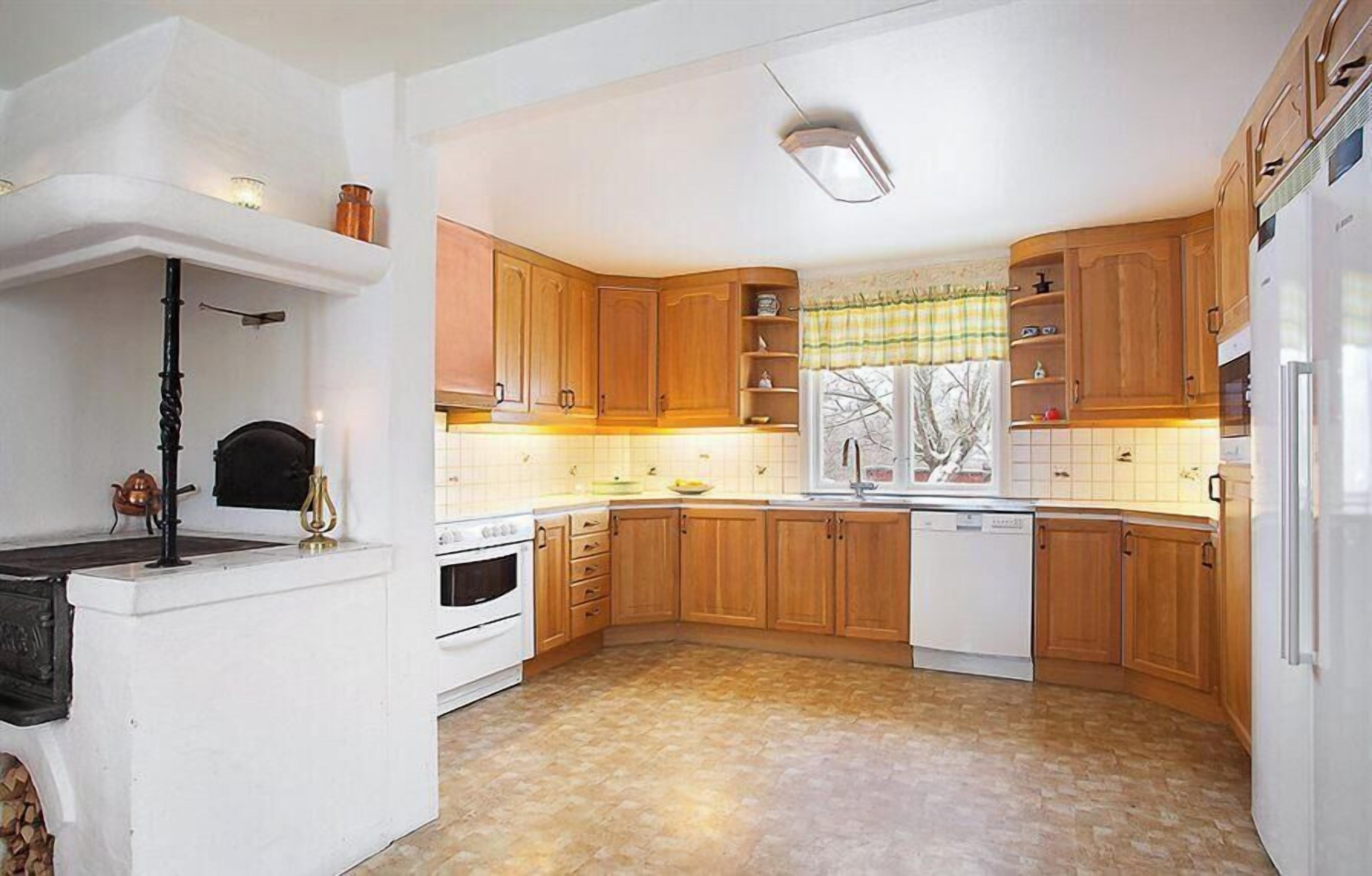 A kitchen with wooden cabinets, a stove, a sink, and a refrigerator.