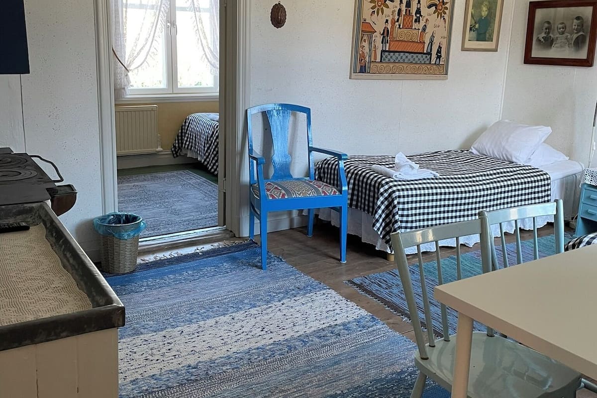 A room with a bed, a chair, a table, and a window.