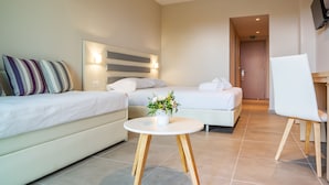 A modern hotel room with a bed, a sofa, a small round table with a plant, and a TV mounted on the wall. - CNic Gemini Hotel (Corfu)