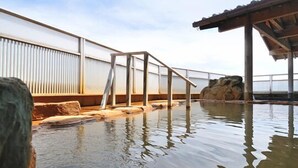 A swimming pool with a wooden deck and a rock formation in the background. - Matsumotoro (Shibukawa)