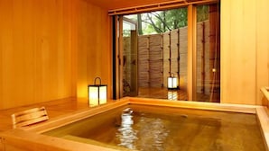 A wooden bathhouse with a large wooden tub, sliding glass doors, and two wall-mounted lanterns. - Matsumotoro (Shibukawa)