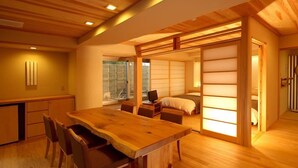 A spacious room with a wooden dining table and chairs, a bed with a sliding shoji screen, and a view of a garden through a large window. - Matsumotoro (Shibukawa)