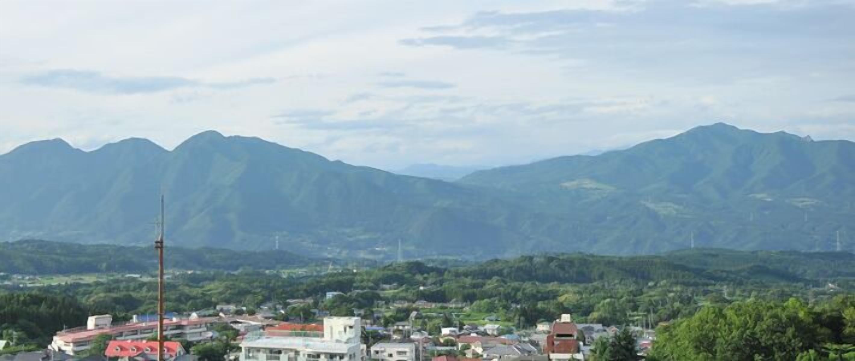 A town with mountains in the background, buildings with red roofs, and a clear sky.