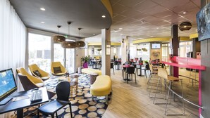 A modern hotel lobby with a large seating area, a reception desk, and a TV screen. - Hôtel Miradour (Dax)