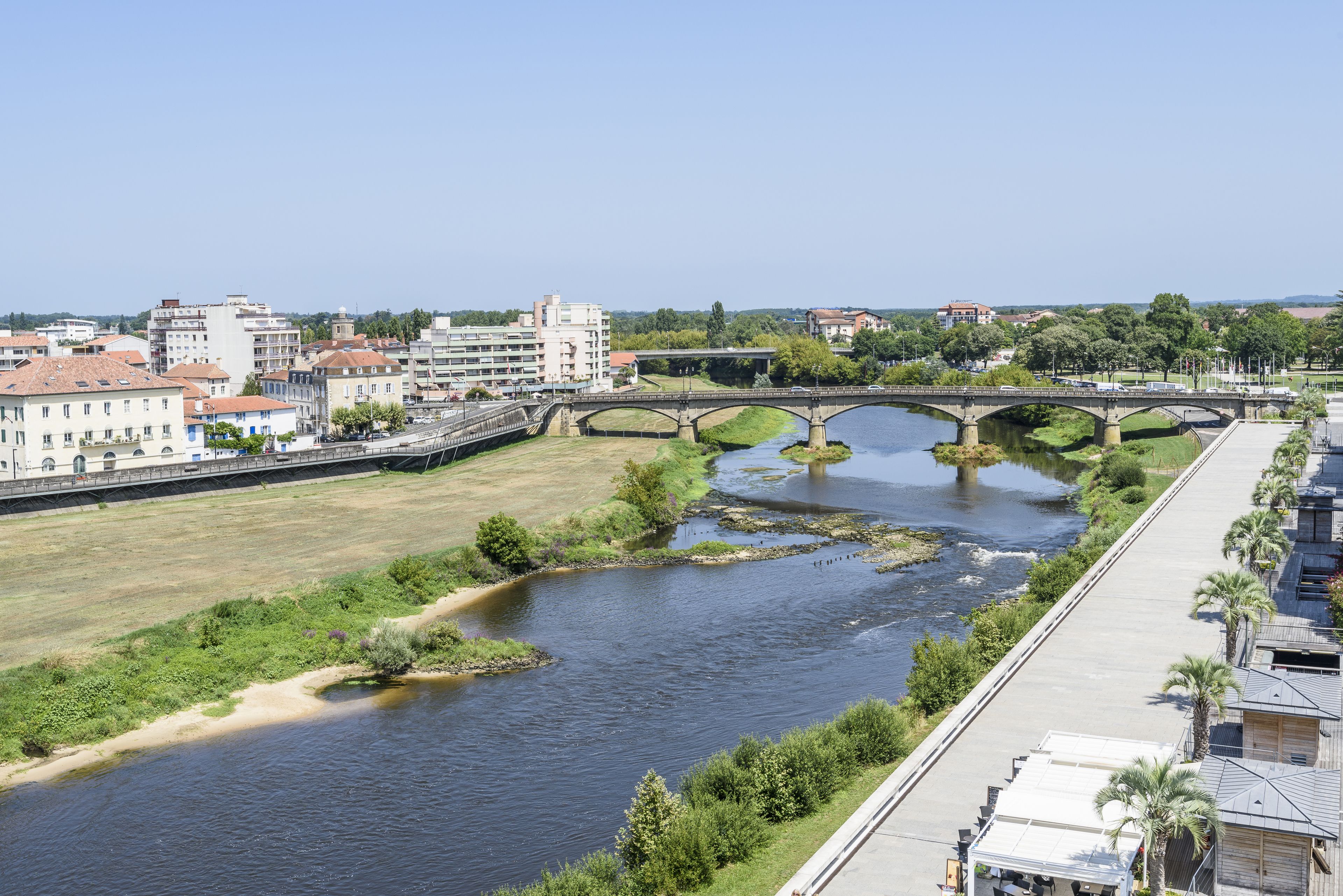 A river with a bridge, buildings, and greenery.