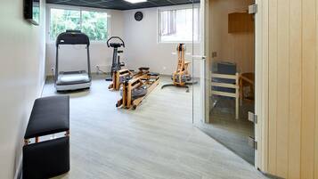 Ein Fitnessraum mit Laufband, Crosstrainer und Trainingsgeräten.