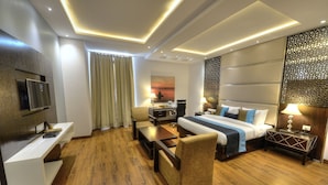 A modern hotel room with a bed, desk, chair, and a TV mounted on the wall. - Hotel Delite Grand (Faridabad)