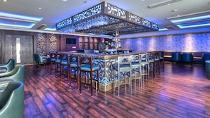 A bar area with a central island, bar stools, and a bartender. - Hotel Delite Grand (Faridabad)