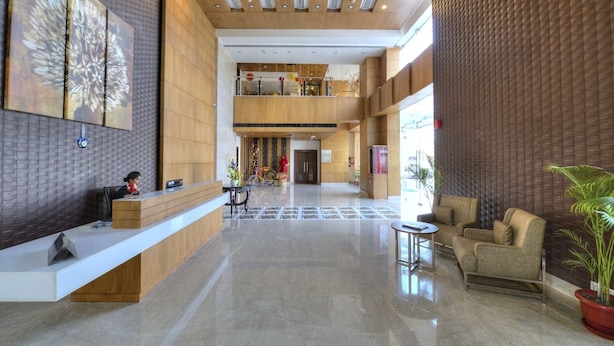 A spacious lobby with a reception desk, seating area, and a staircase leading to an upper level. - Hotel Delite Grand (Faridabad)