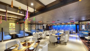 A modern restaurant with white furniture, blue seating, and decorative hanging lights. - Hotel Delite Grand (Faridabad)