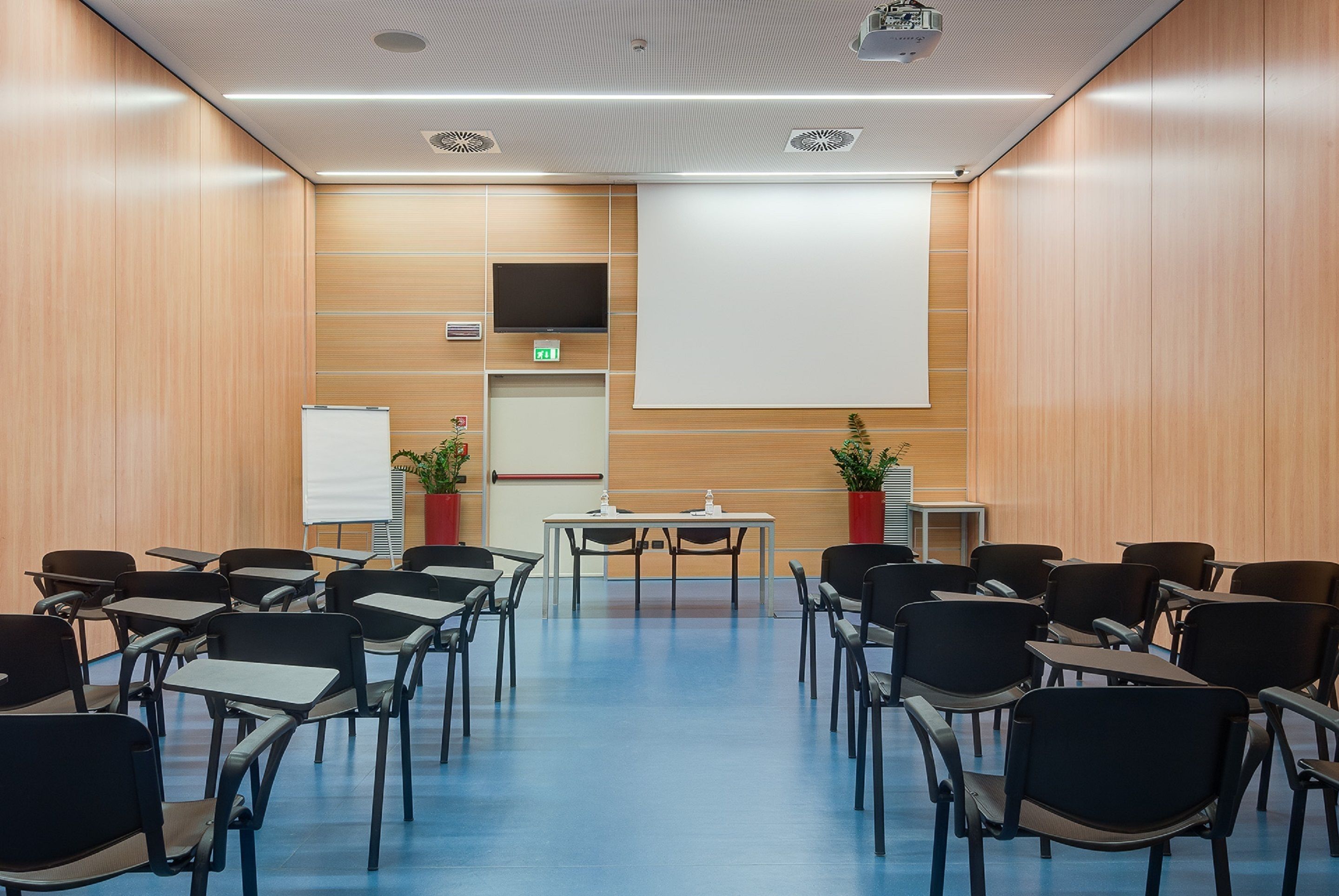 A conference room with a large screen, a whiteboard, and a projector.