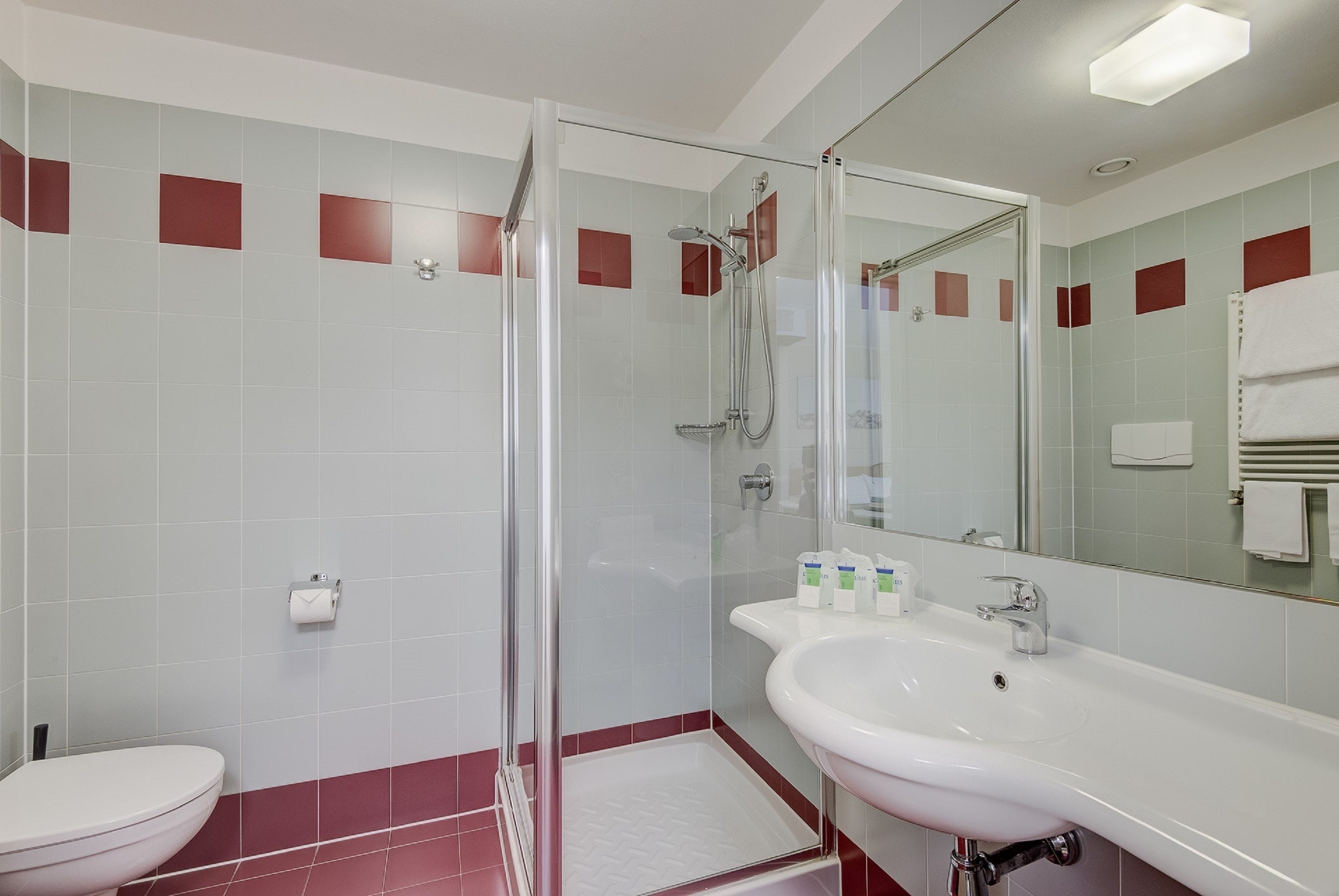 Et moderne badeværelse med bruseniche, hvid vask og toilet.