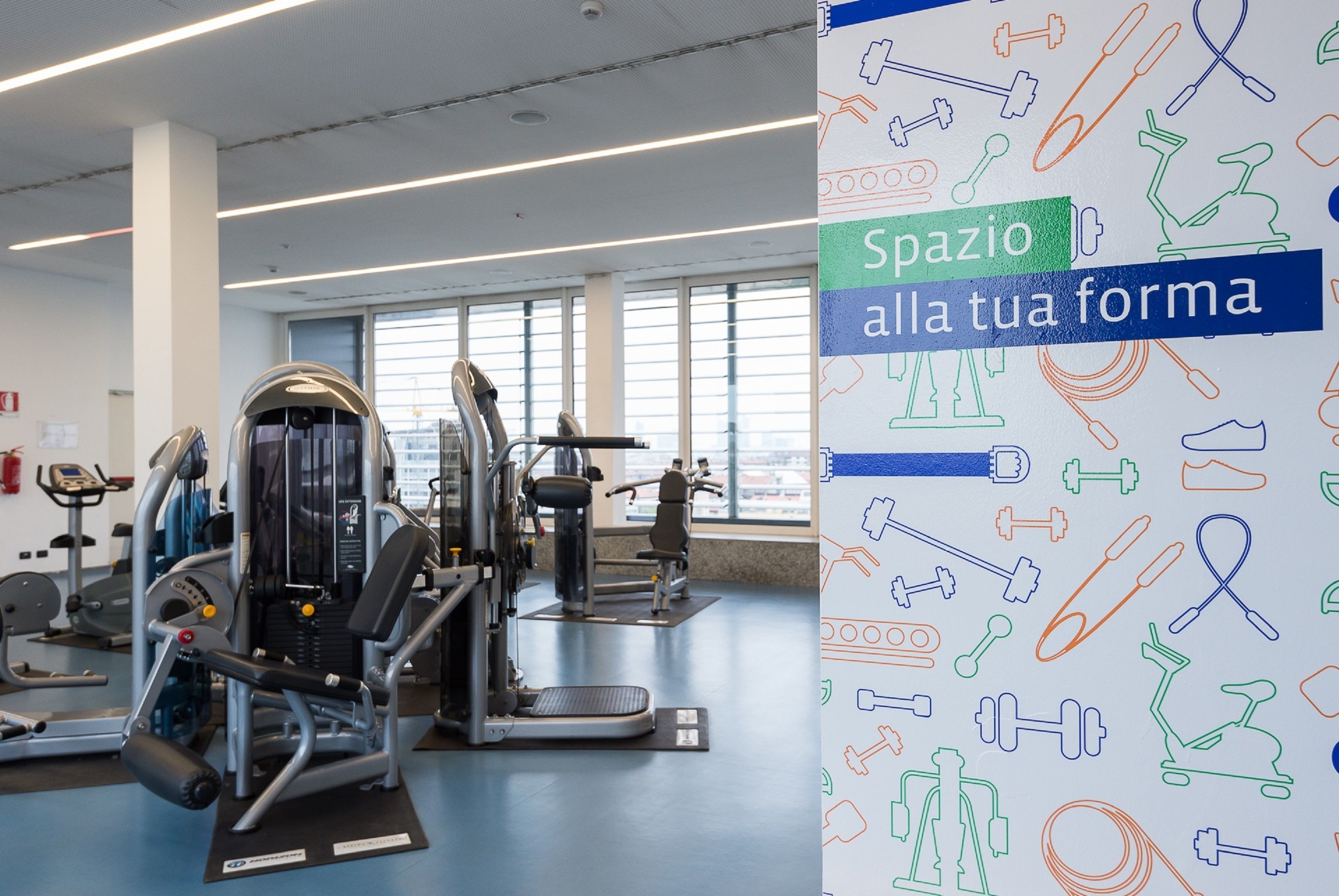 A gym with exercise equipment and large windows.