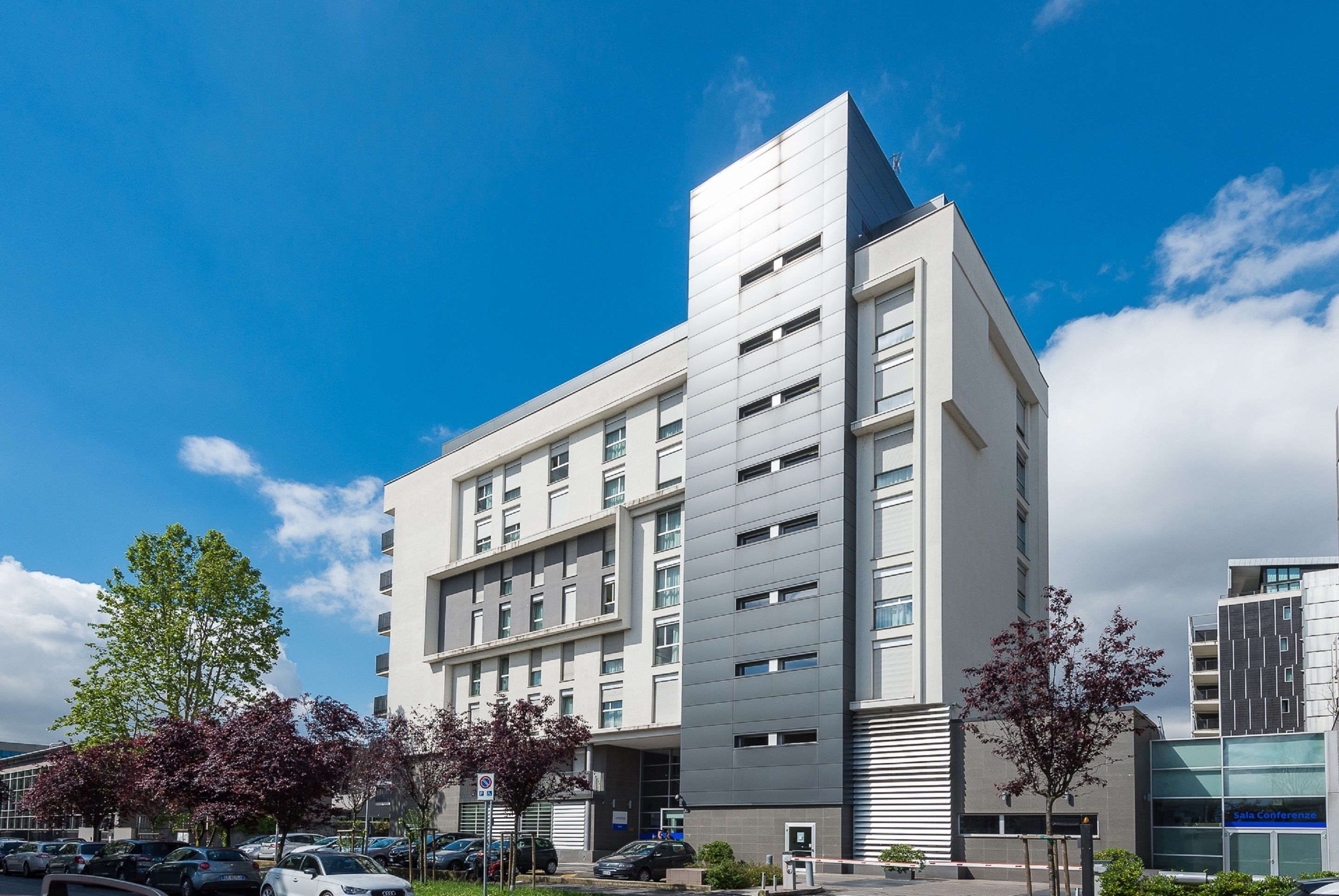 A modern multi-story building with a flat roof and a prominent corner section.