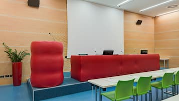 A modern conference room with a red podium, green chairs, and a white table.