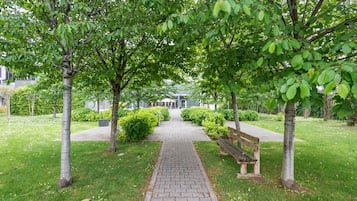 Un camino pavimentado en un parque, con bancos y árboles.