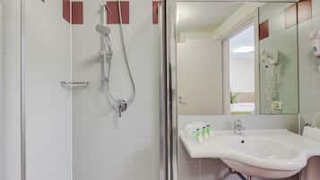 A bathroom with a shower, sink, and mirror.