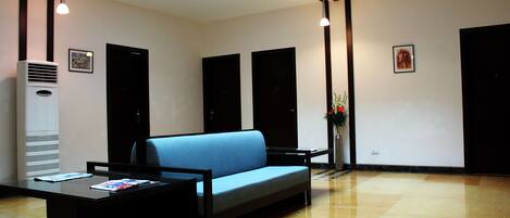 A modern lobby with a blue sofa, a black coffee table, and a ceiling light.