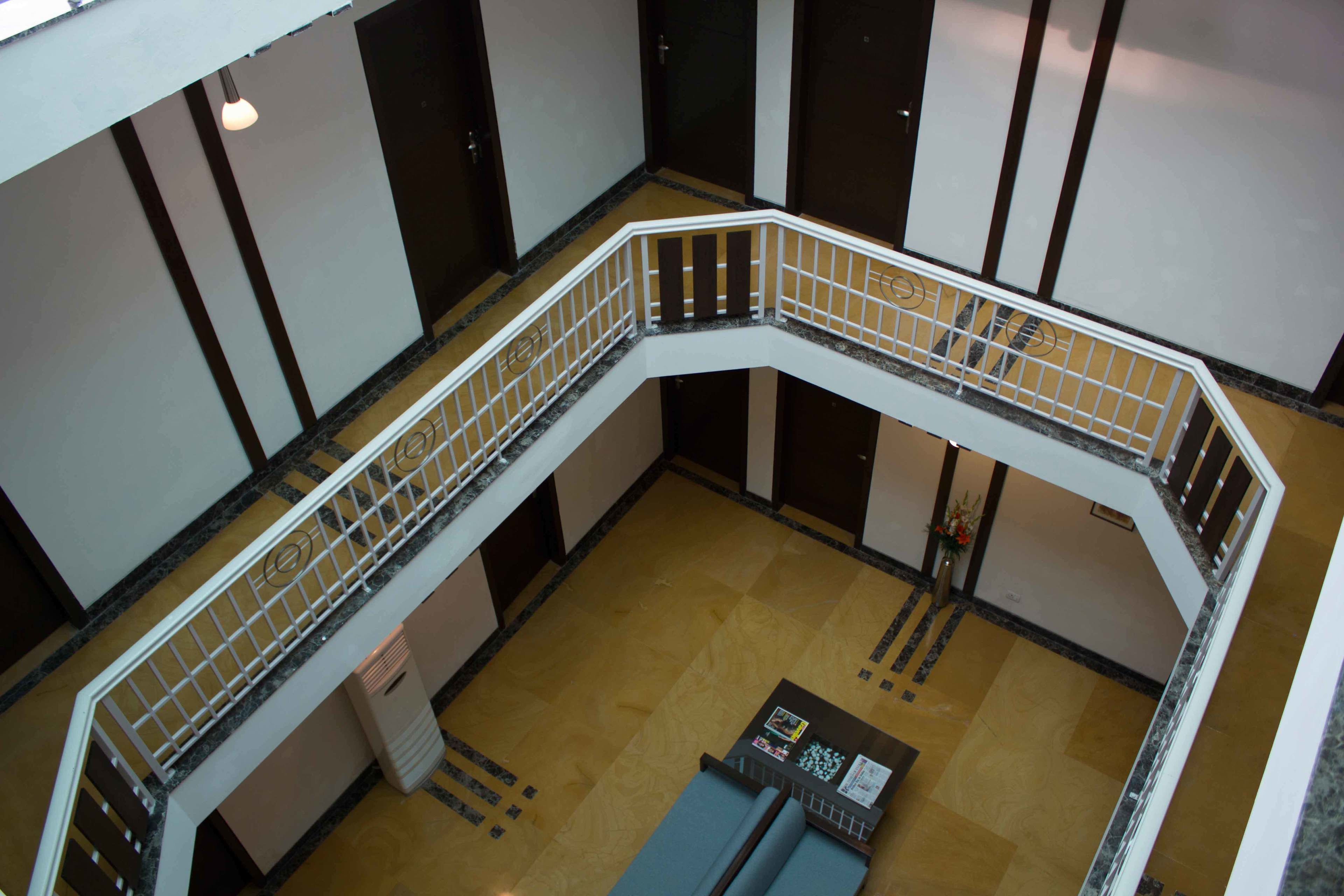 A multi-level interior with a curved white railing, a central seating area, and a patterned floor.