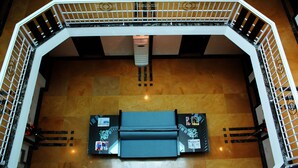 A spacious lobby with a high ceiling, a central seating area, and a modern staircase with a metal railing. - Stately Suites MG Road (Gurugram)