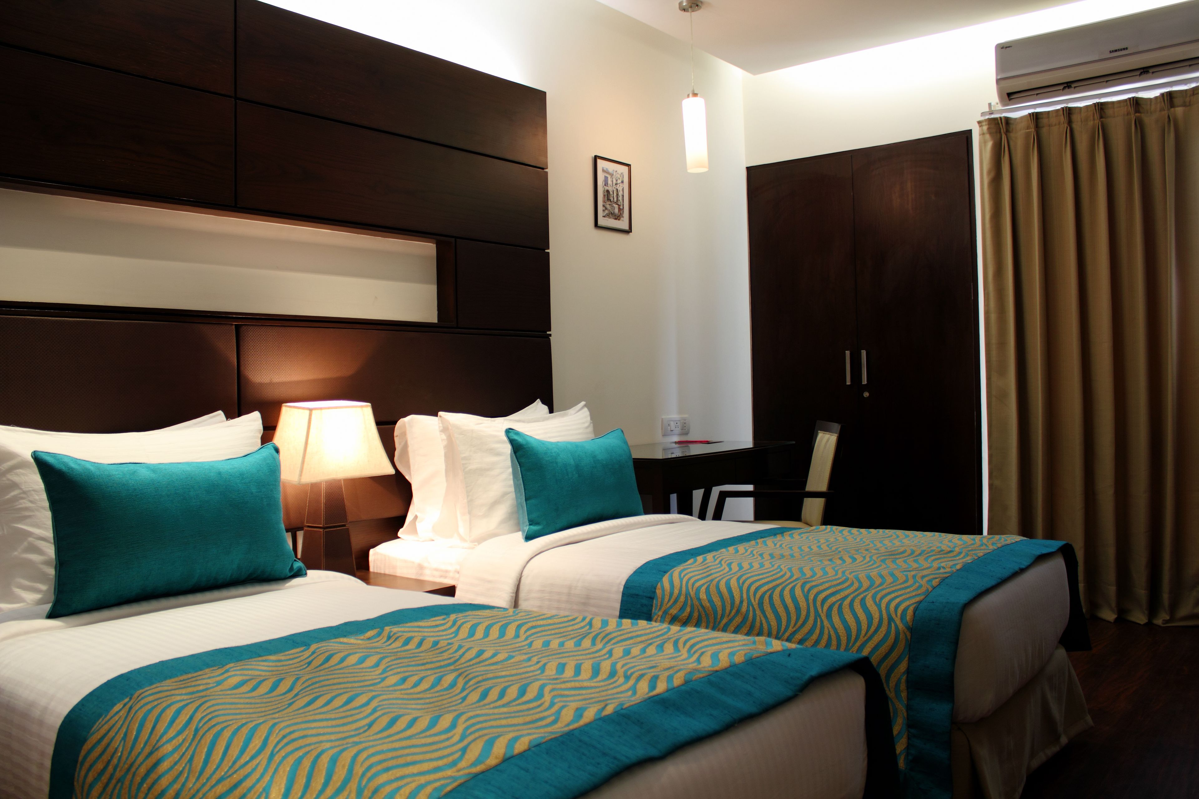 A hotel room with two beds, a desk, and a wardrobe.