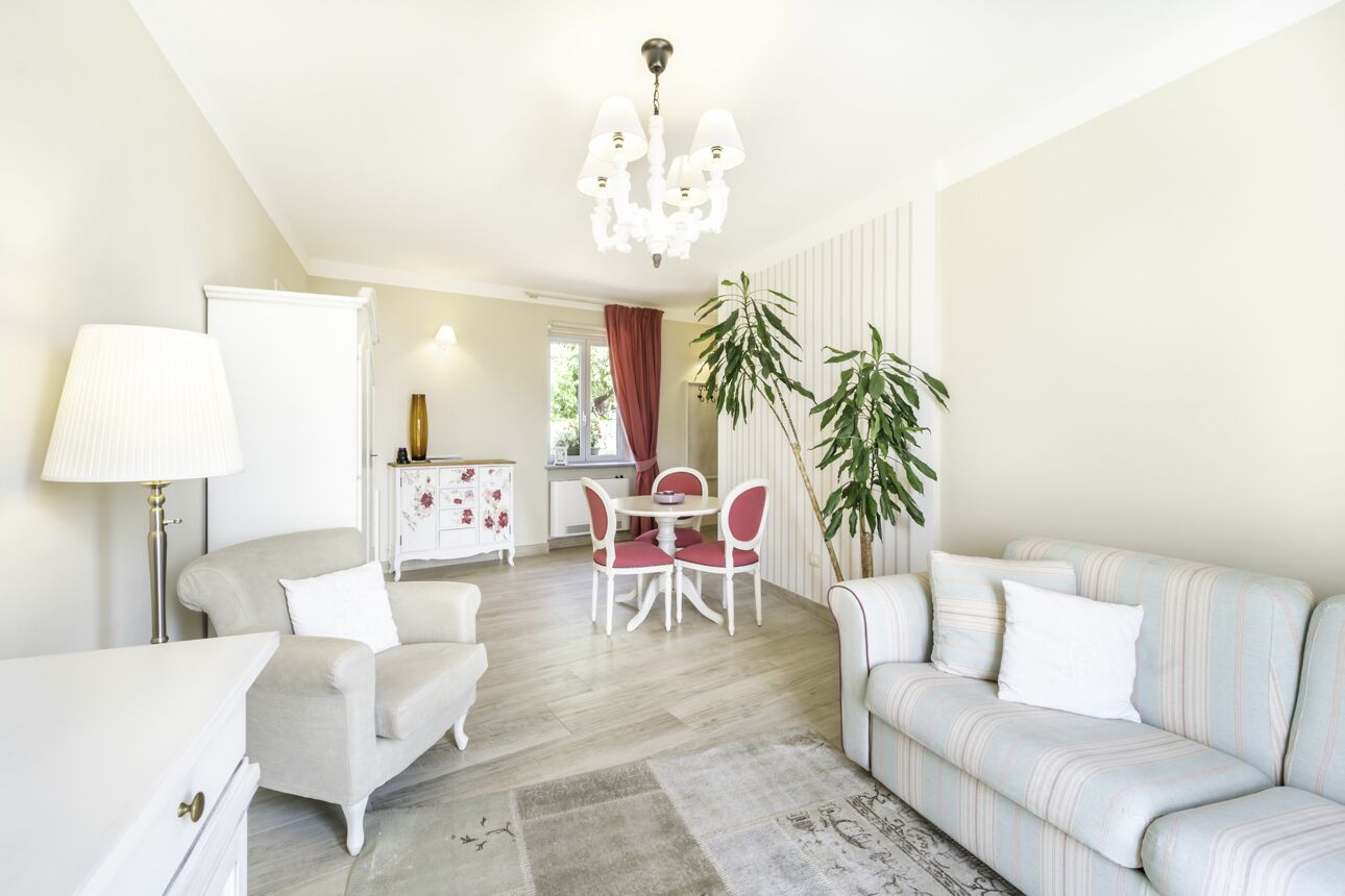 Una sala de estar moderna con un sofá, una mesa de comedor con sillas, una lámpara y un candelabro.