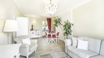 Una sala de estar moderna con un sofá, una mesa de comedor con sillas, una lámpara y un candelabro.