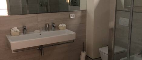 Un baño moderno con un espejo grande, un lavabo y un inodoro.