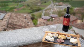 Un repisa de piedra con una tabla de quesos, dos copas de vino tinto y una botella de vino.