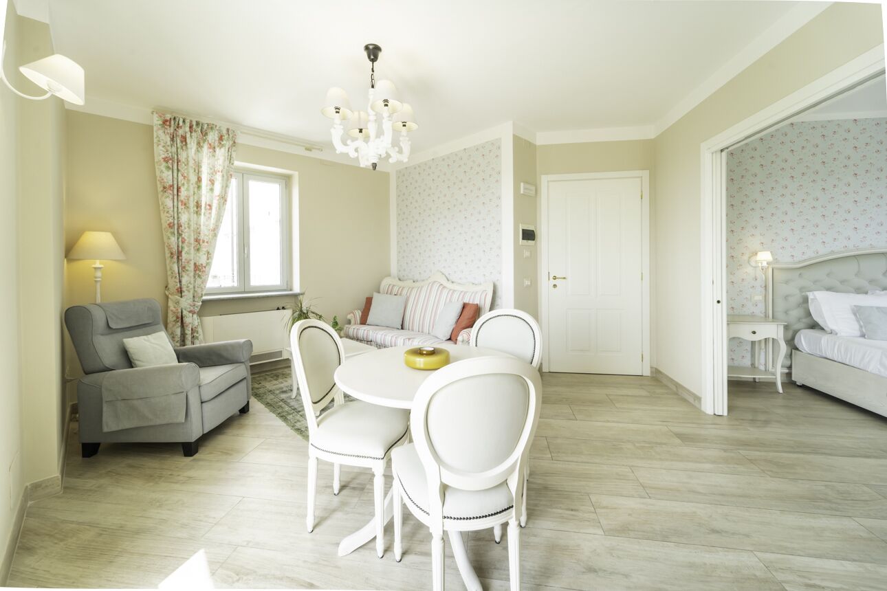 A room with a dining table, chairs, a sofa, and a bed.