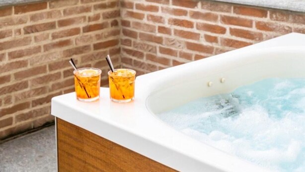 A hot tub with two drinks on a balcony overlooking a landscape. - Locanda Borgo Vecchio (Neive)