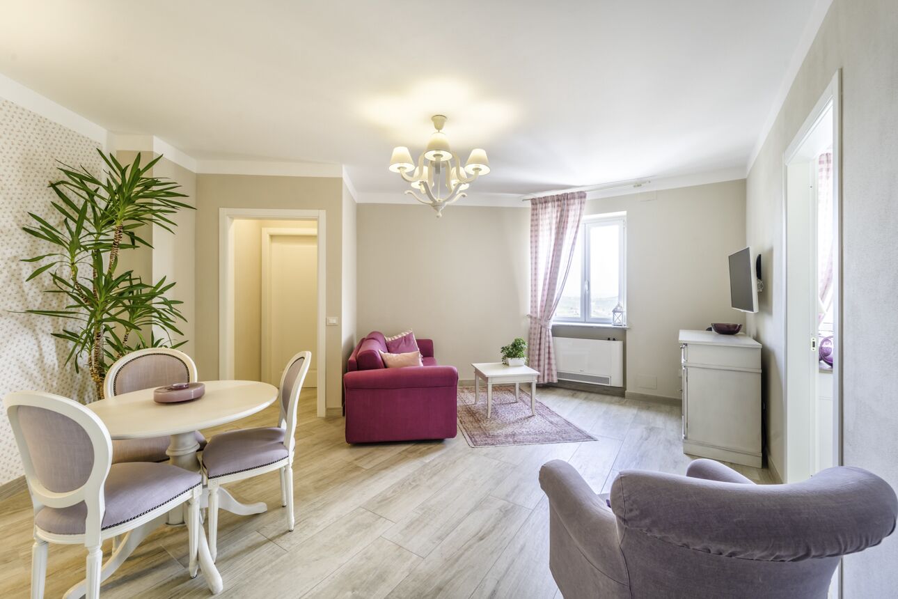 Una sala de estar con una mesa de comedor, un sofá púrpura y un televisor sobre un mueble.