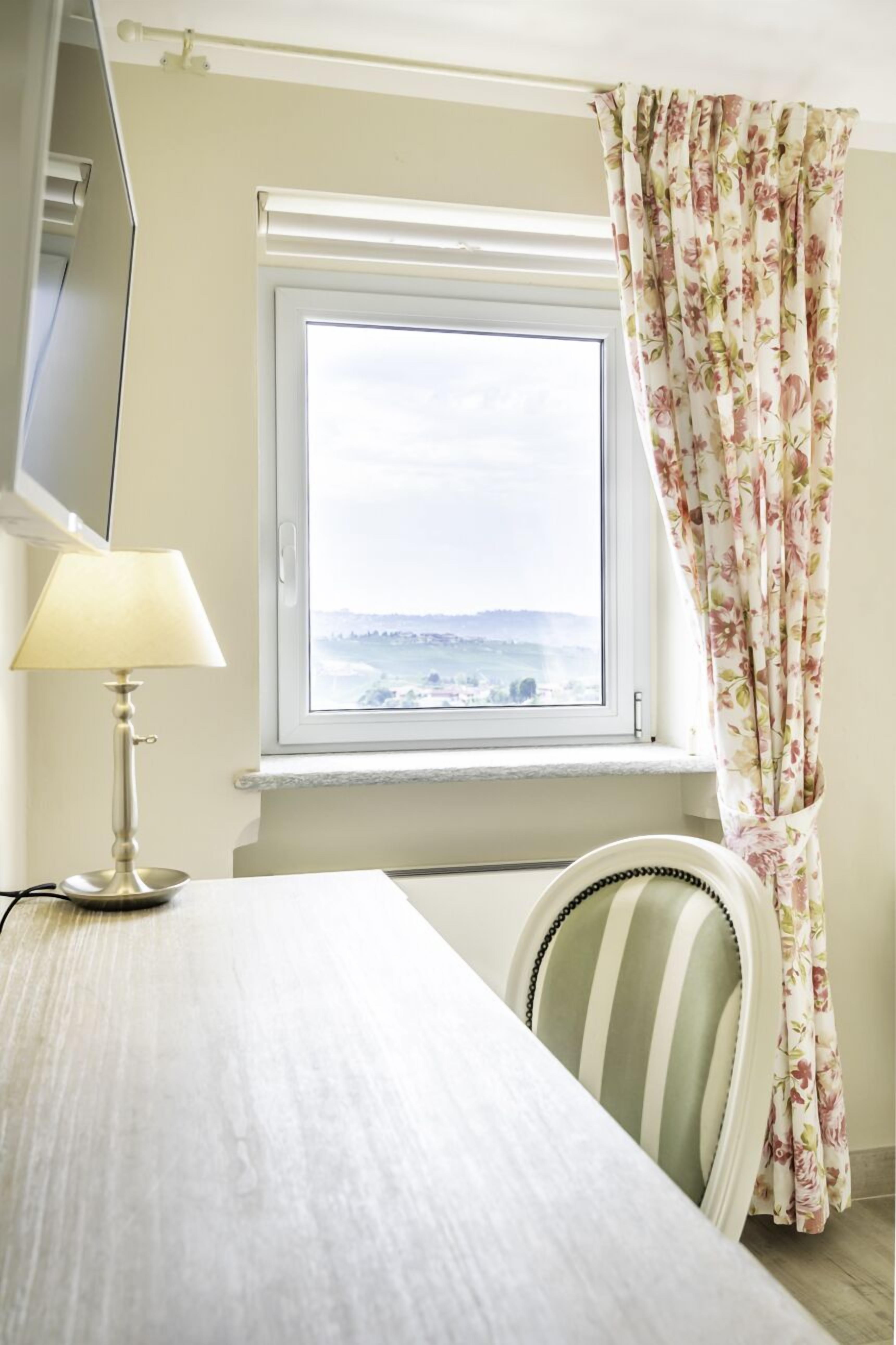 A room with a window, a lamp, a chair, and a bed.