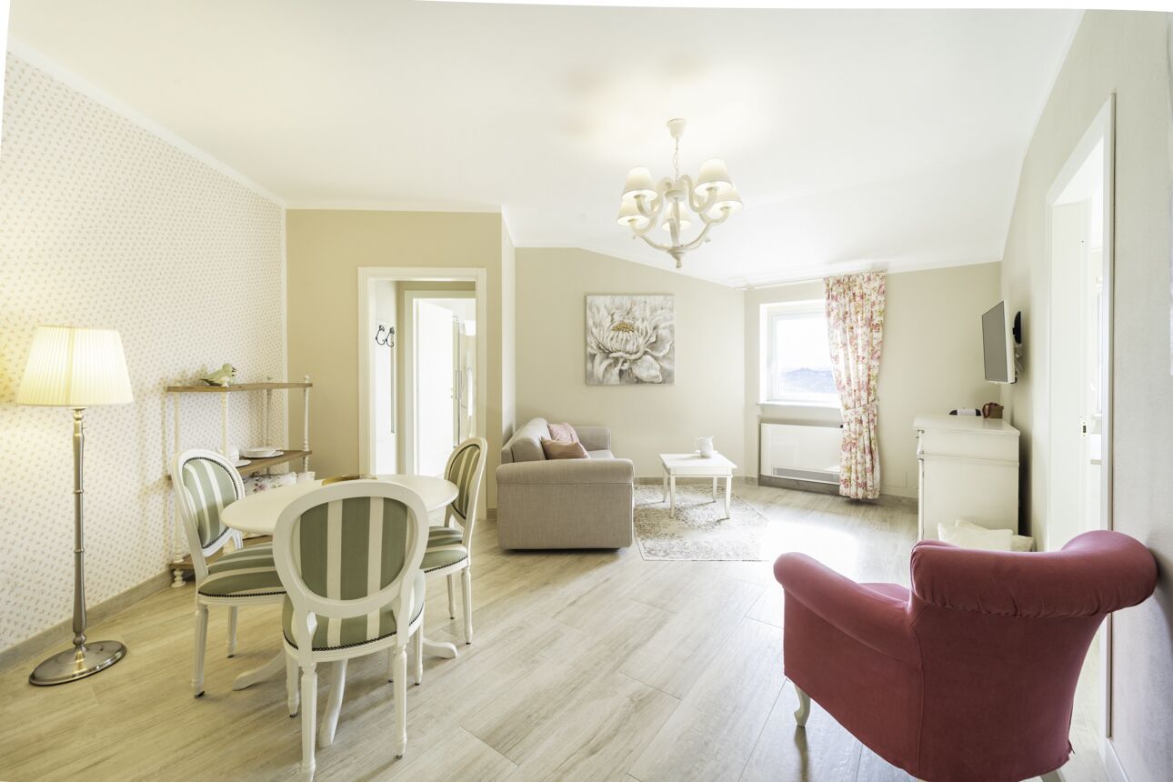A spacious living area with a dining table, chairs, a sofa, and a red armchair.