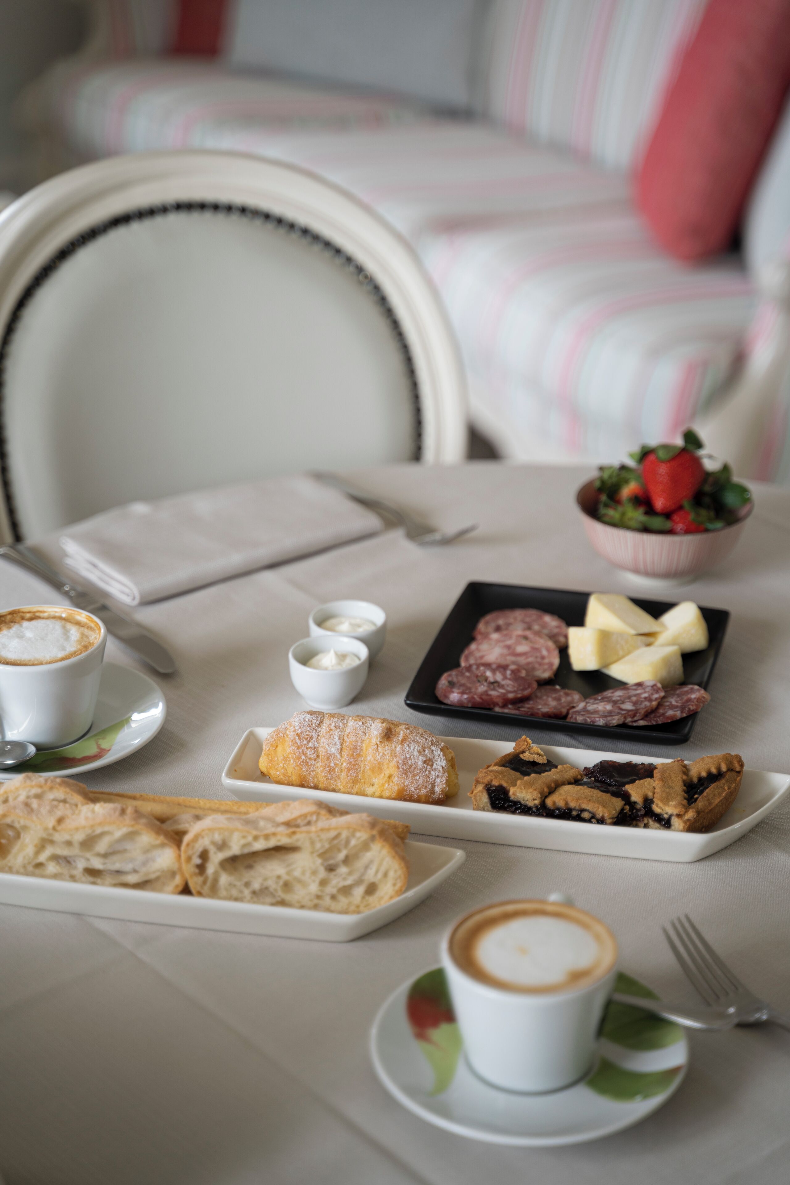Une table dressée pour le petit-déjeuner, avec des viennoiseries, du fromage et du café.