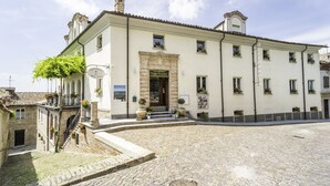 A building with a central entrance, multiple windows, and a cobblestone courtyard. - Locanda Borgo Vecchio (Neive)