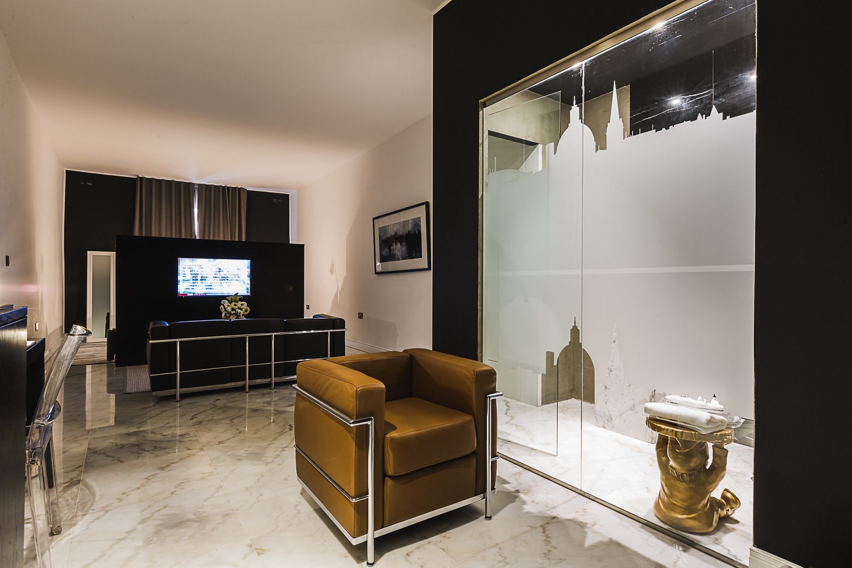 A modern living room with a sofa, a TV, and a glass partition with a cityscape view.
