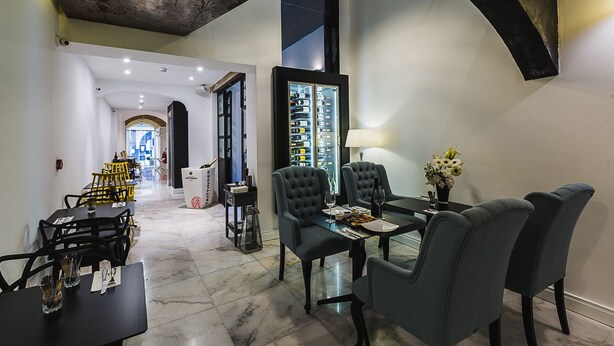 Un espace de salle à manger moderne avec une table en verre, des chaises foncées et un présentoir à vin.
