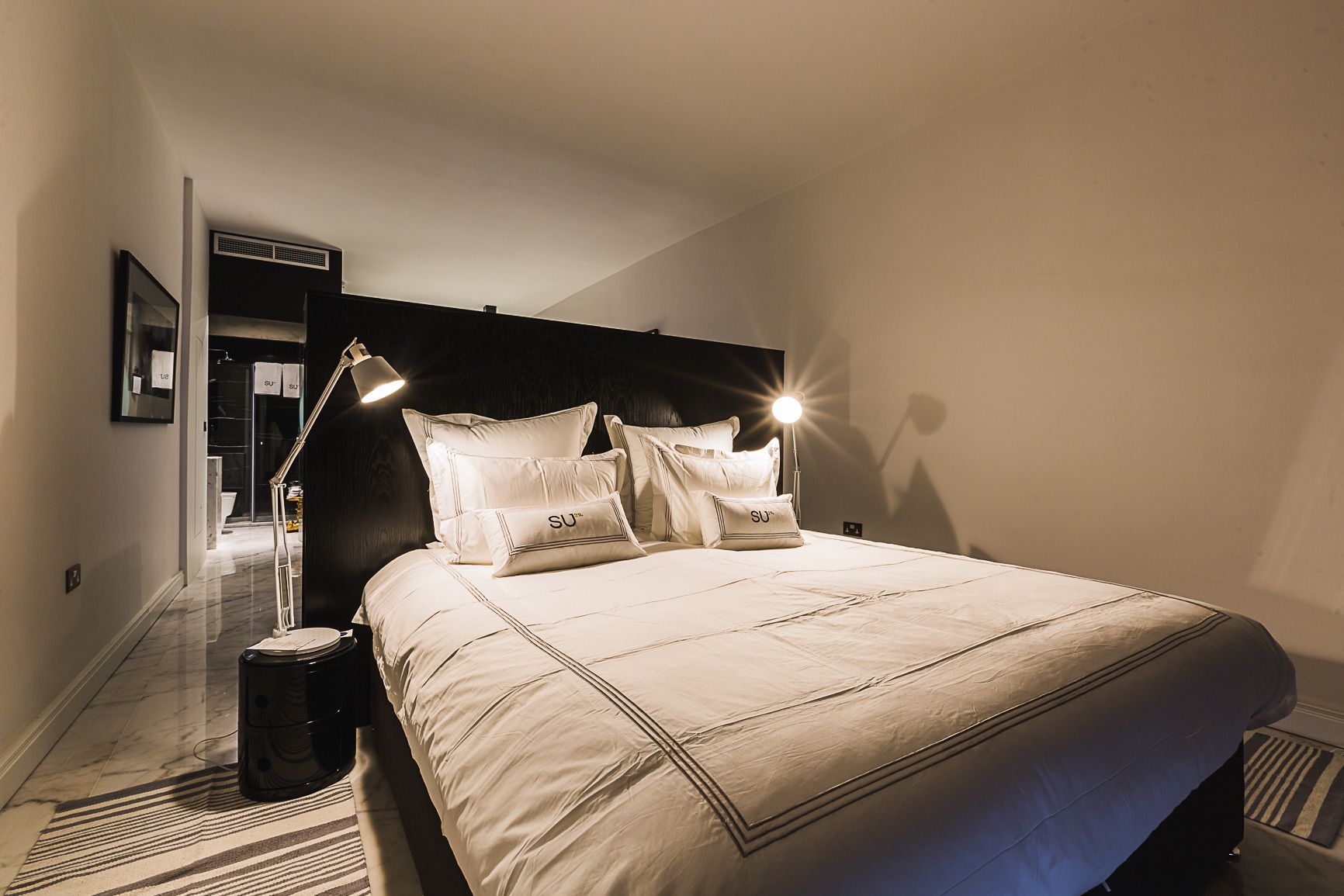 A neatly made bed with a headboard, a bedside lamp, and a nightstand.