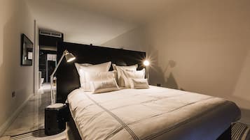 Una cama bien hecha con cabecera, lámpara de noche y mesita de noche.