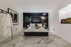 A modern bedroom with a large bed, a mirror, a robe, and a bookshelf. - SU29 Boutique Hotel (Valletta)
