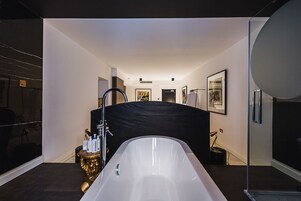 A modern bathroom with a freestanding bathtub, a black partition, and a gold decorative item.
