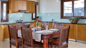 Una cocina moderna con armarios de madera, una mesa de comedor preparada para cuatro personas y un ventanal con vistas al exterior.
