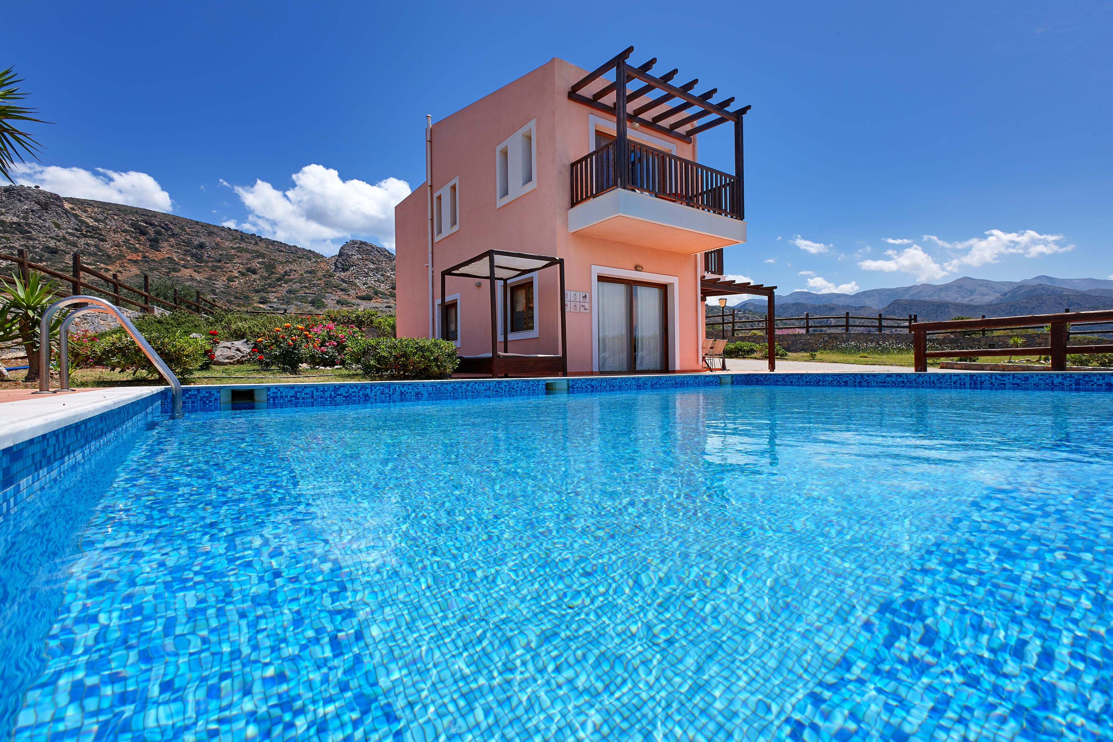 Un bâtiment à deux étages doté d’un balcon, d’une piscine et surplombant un paysage montagneux.