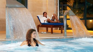 A pool area with a person relaxing on a lounge chair and another person in the water. - Vasia Sea Retreat - Adults Only. (Agios Nikolaos)